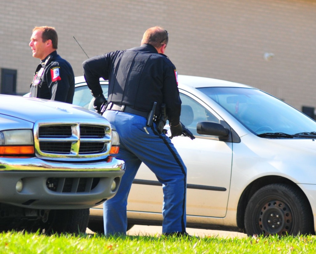 Assistant Police Chief Nathan Schmitt and an unidentified officer holding a handgun at the scene.