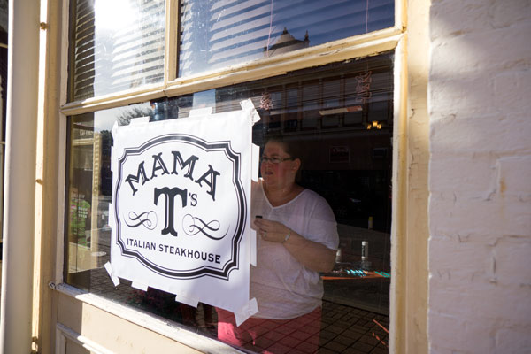 Sarah Schmitt painted Mama T's sign on the restaurant front windows Monday afternoon.