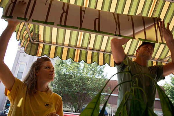 Anna (Steckler) Catt and Aaron Catt apply the new sign to their business on Fourth Street in Huntingburg. The couple, just married in June, have been planning the name change from Cool Beans for months. Starting Monday, August 1, the long-time cafe will open with new name and new hours. Milk Parlor will be open Mondays through Fridays 7 a.m. to 2 p.m. and Saturdays 7:30 a.m. to 11 a.m.