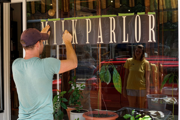 Anna (Steckler) Catt inspects the new sign as Aaron finishes.