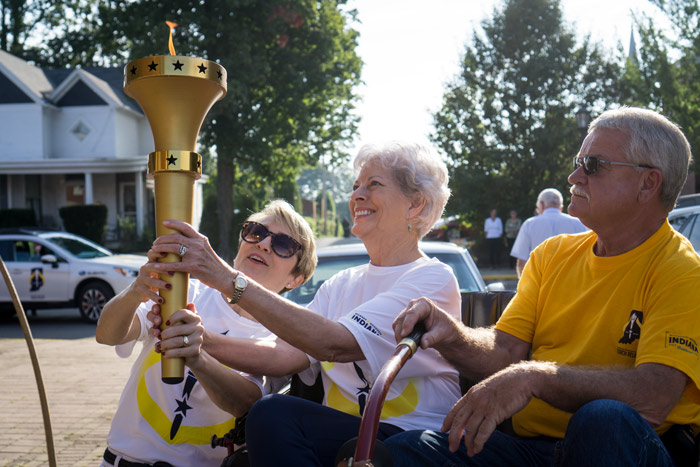Former Lt. Gov. Sue Ellspermann passes the torch to Huntingburg's Connie Nass. Nass and Ellspermann are the only two Dubois County women to have held state offices. Nass and Jeff Tisdal drove the 1901 Huntingburg Tour Car down Fourth Street before handing the torch to Lee Bilderback.