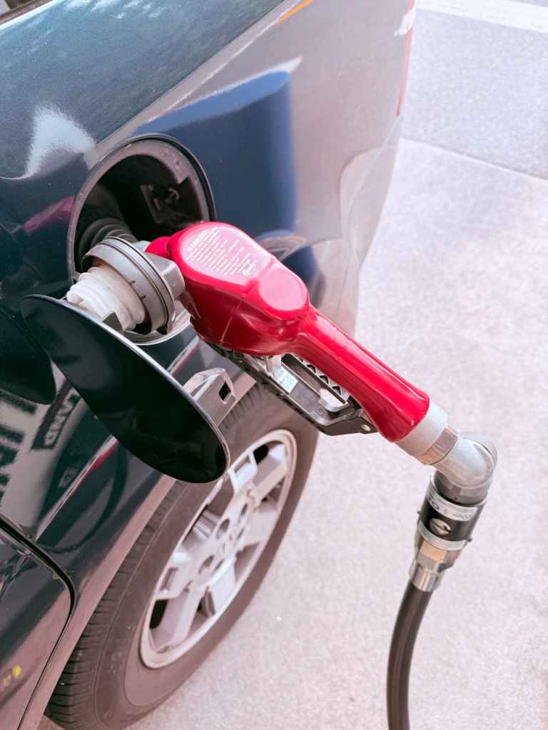 red gas pump refueling a car at station